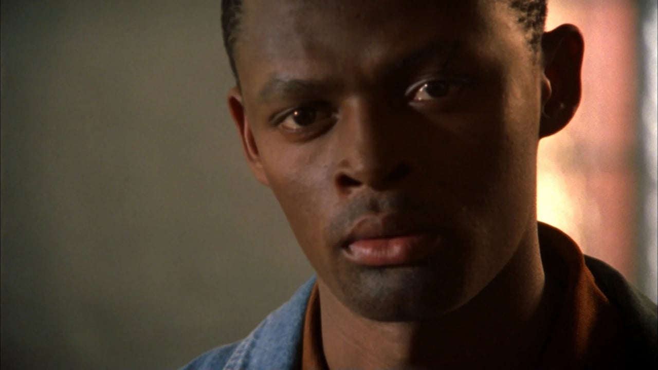 Close-up portrait of a man with a serious expression, lit with warm light from the right.